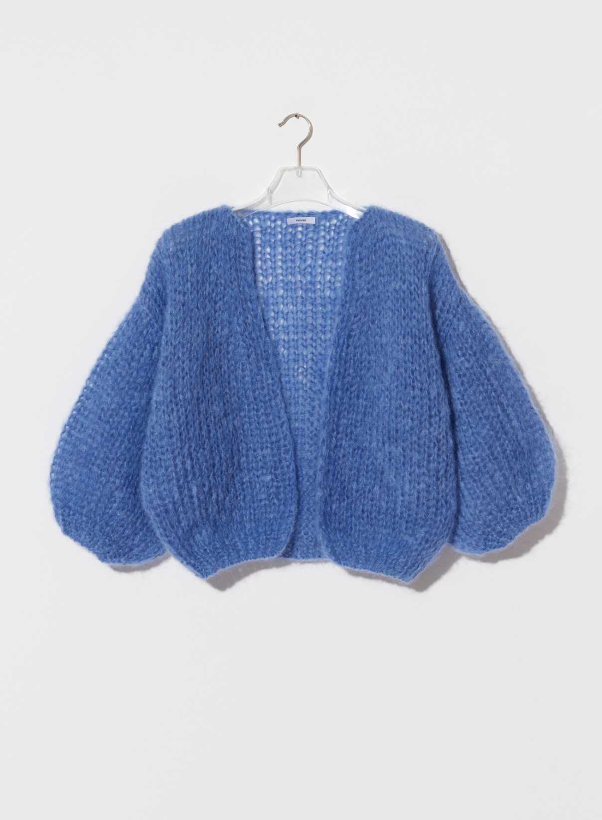 Blue knitted cardigan on a hanger against a white background