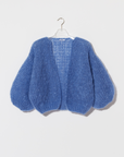 Blue knitted cardigan on a hanger against a white background