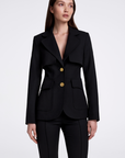Woman wearing a black blazer with gold buttons on a white background