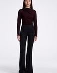 Woman wearing a brown long-sleeve top and black pants on a white background