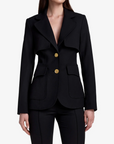 Woman wearing a black suit with gold buttons on a white background