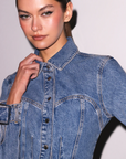 Woman wearing a blue denim jacket against a plain background