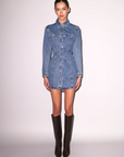 Woman wearing a denim dress with black knee-high boots on a white background