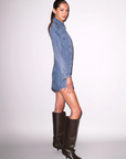 Woman wearing a denim dress and brown knee-high boots on a white background