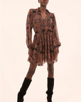 Woman wearing a patterned dress and black boots on a beige background