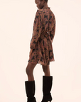 Woman wearing a patterned dress and black high-heeled boots on a white background