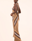 Woman wearing a long, patterned dress with a plain background