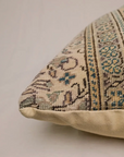 Patterned pillow with beige border on a light background