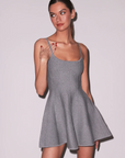 Woman wearing a gray dress with cut-out sides on a plain background