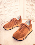Pair of brown suede shoes on a textured white surface