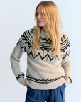 Woman wearing a patterned sweater against a plain background
