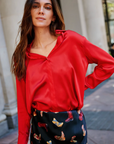 Woman wearing a red blouse and patterned skirt outdoors