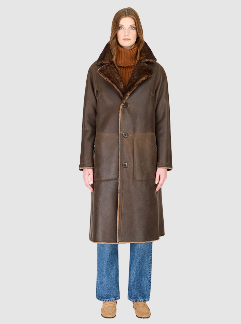 Person wearing a brown leather coat with fur lining on a white background