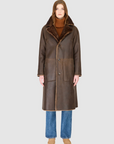 Person wearing a brown leather coat with fur lining on a white background