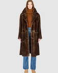 Person wearing a brown shearling coat on a white background