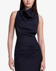 Woman wearing a sleeveless navy dress against a white background