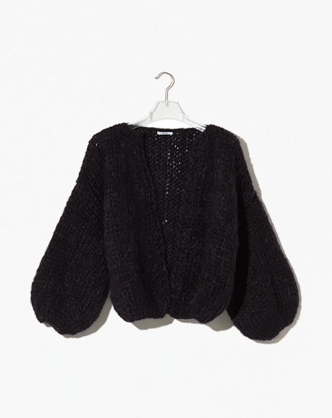 Black knitted cardigan on a hanger against a white background