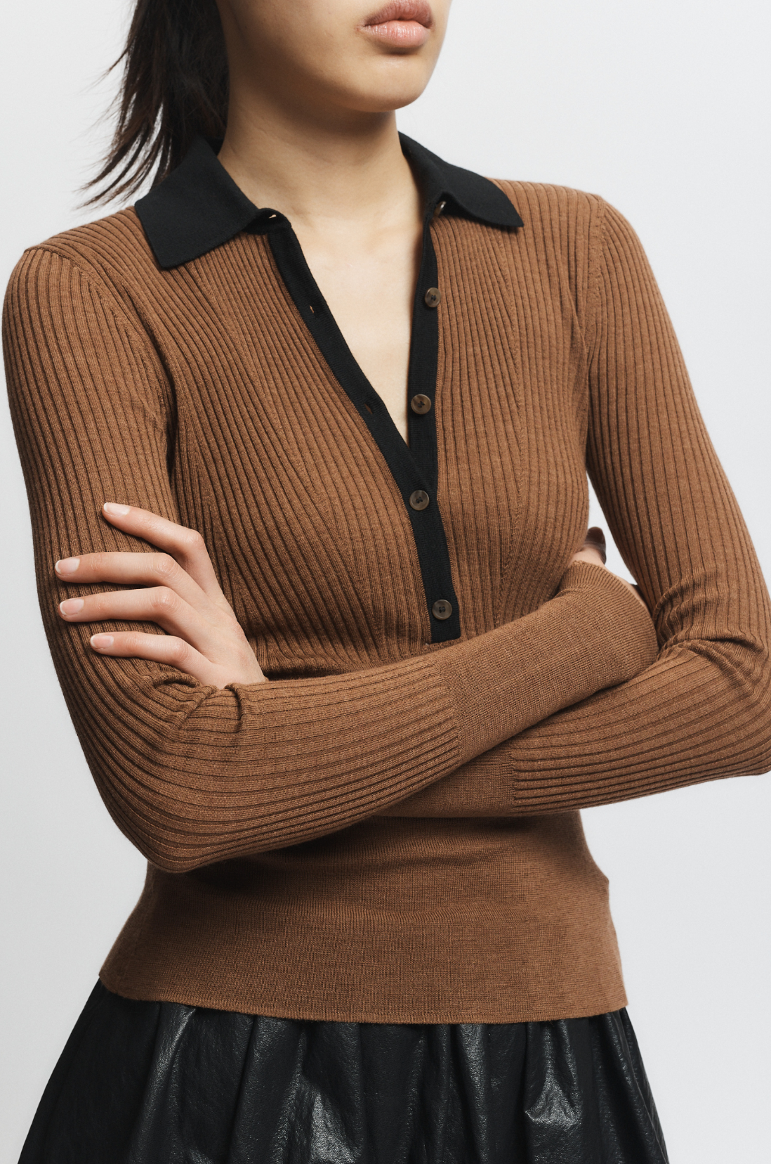 Brown ribbed sweater with black collar and buttons on a white background