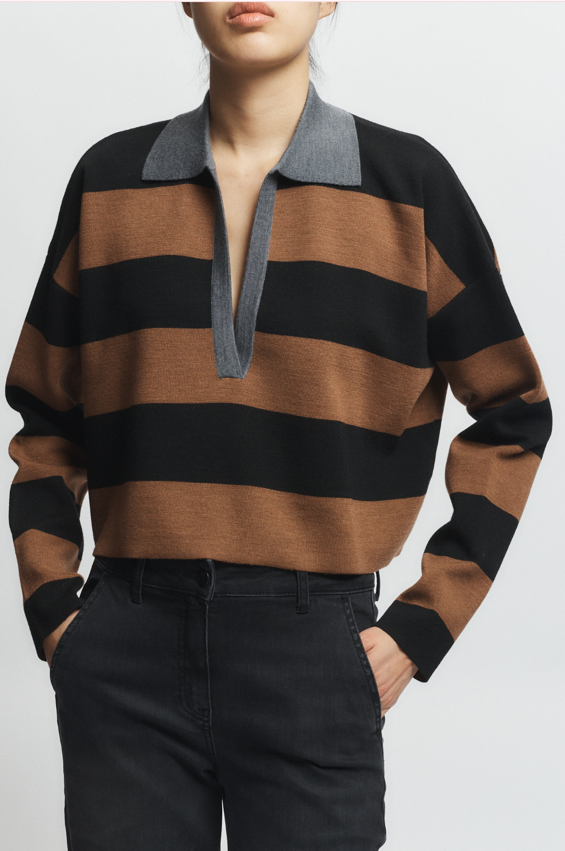 Person wearing a brown and black striped sweater with a gray collar on a white background