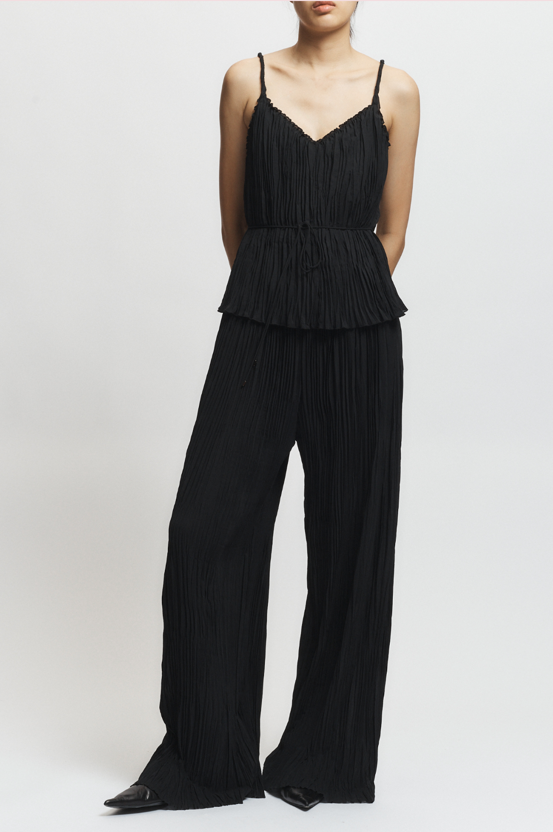 Black jumpsuit with peplum top and wide-leg pants on a white background