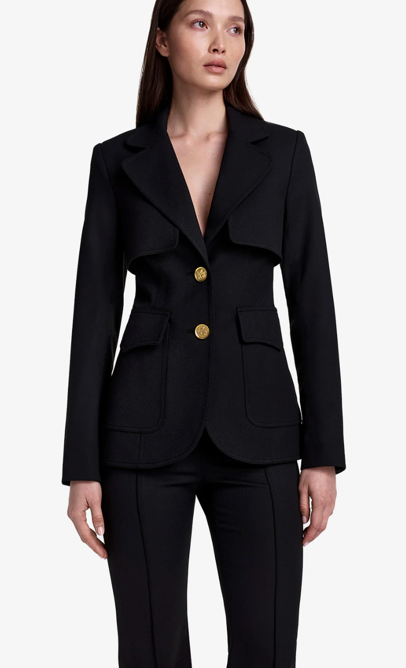 Woman wearing a black suit with gold buttons on a white background