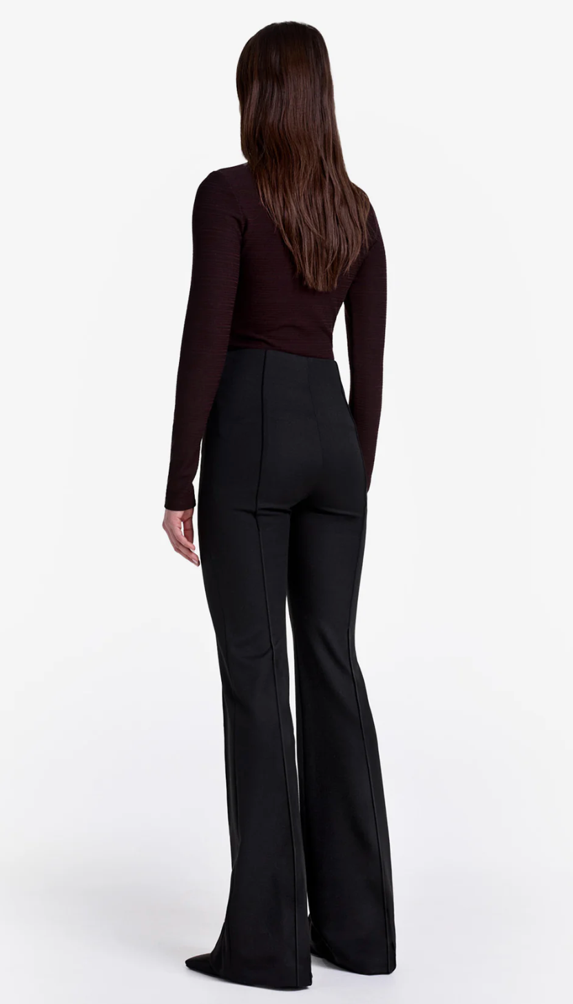 Person wearing a black outfit with wide-leg pants on a white background