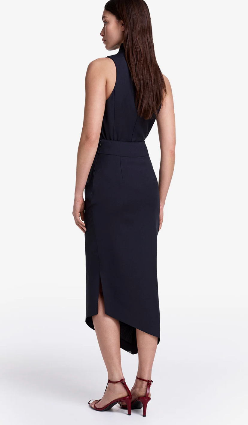 Woman wearing a black sleeveless dress with a slit on a white background
