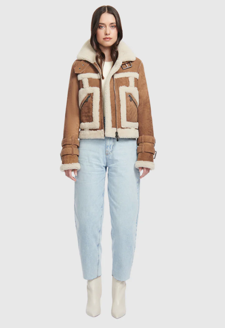 Woman wearing a brown shearling jacket with geometric patterns on a white background