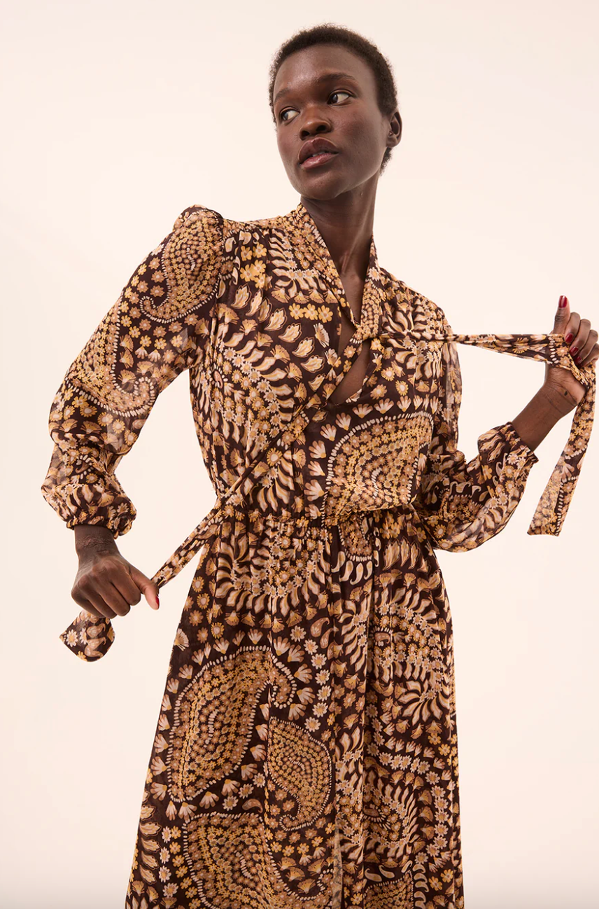 Woman wearing a patterned dress against a plain background