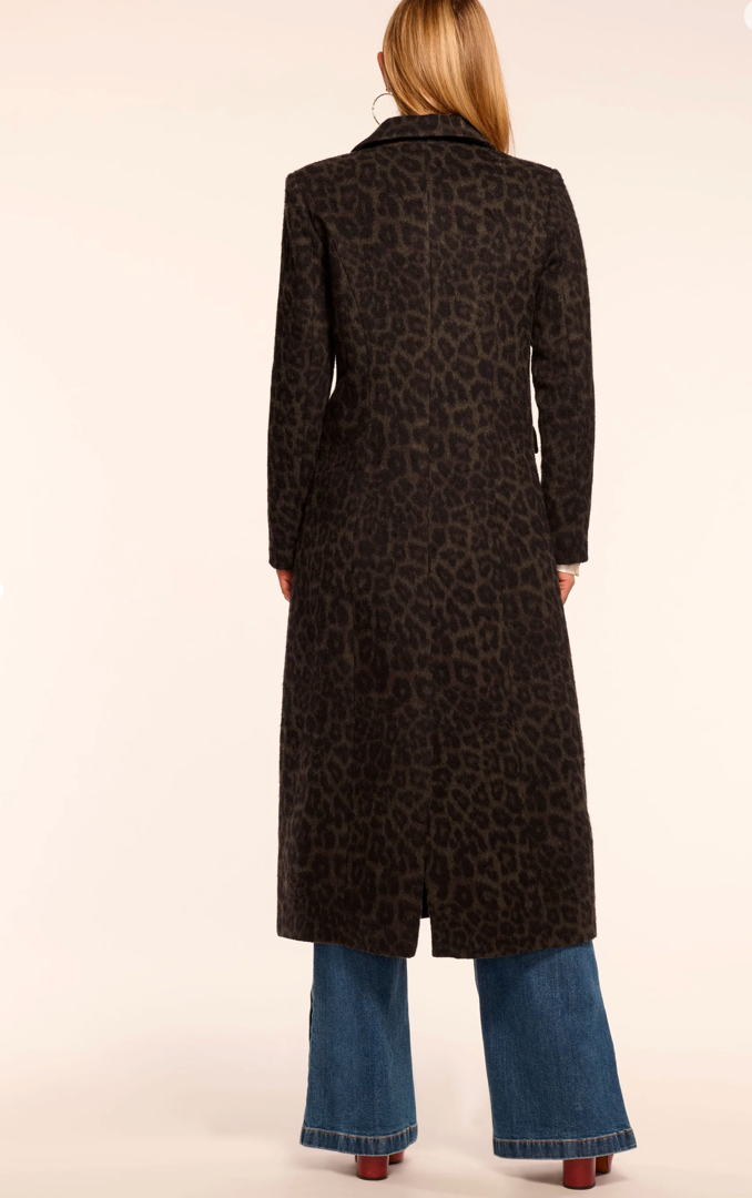 Person wearing a long black coat with a leopard print pattern on a beige background