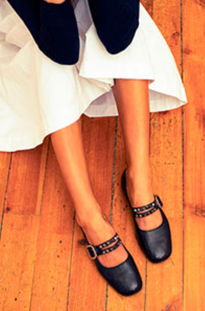 Black shoes with studded details worn on a wooden floor
