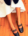 Black shoes with studded details worn on a wooden floor