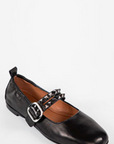 Black flat shoe with a brown insole on a white background