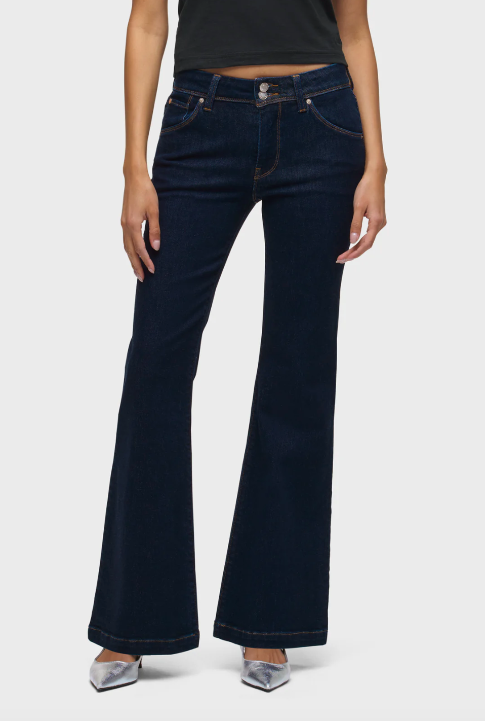 Person wearing dark blue flared jeans on a white background
