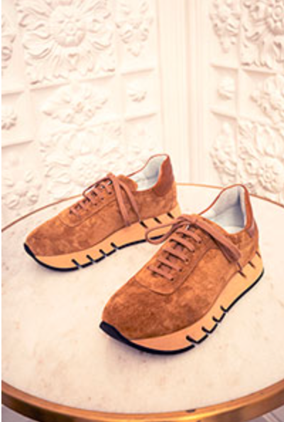 Pair of brown suede shoes on a textured white surface