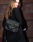 Woman carrying a black handbag against a brown textured wall