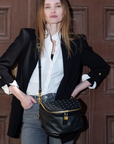Woman holding a black studded handbag against a wooden door background