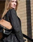 Woman carrying a black backpack with a brown patch on a brick building background
