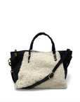 Black handbag with a white shearling liner on a white background