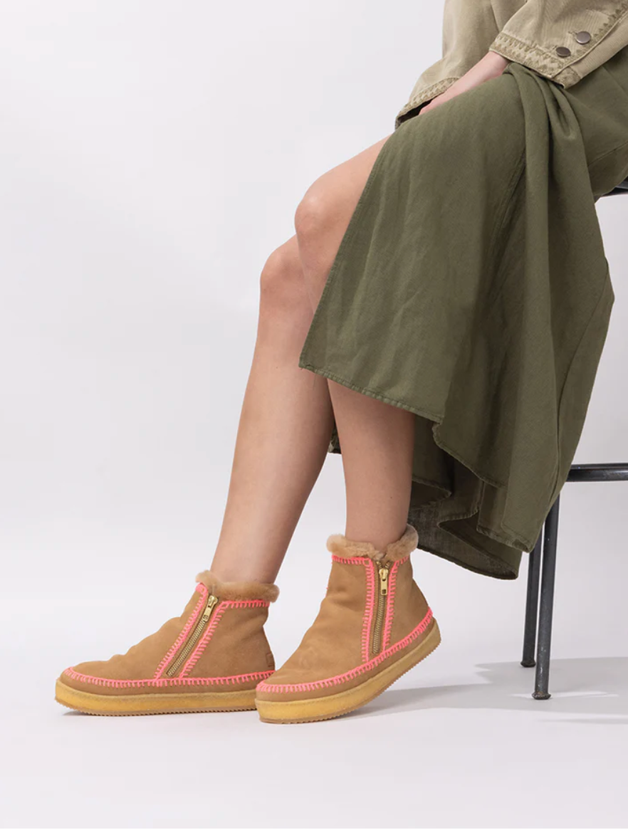 Person wearing brown boots with pink accents sitting on a chair.