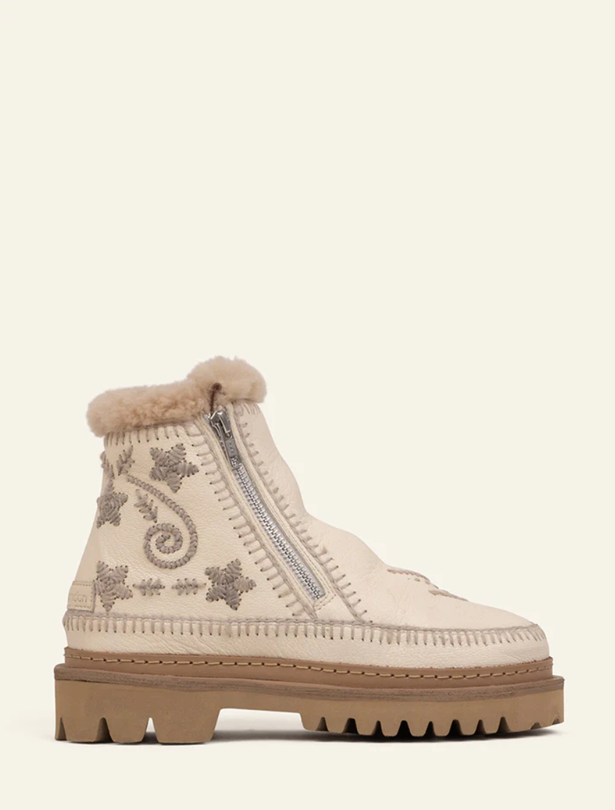 White ankle boot with decorative patterns and fur trim on a white background
