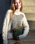 Woman holding a green book or folder outdoors on steps