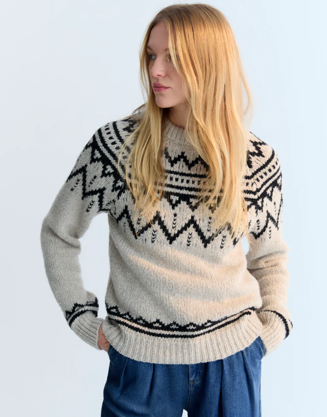 Woman wearing a patterned sweater against a plain background