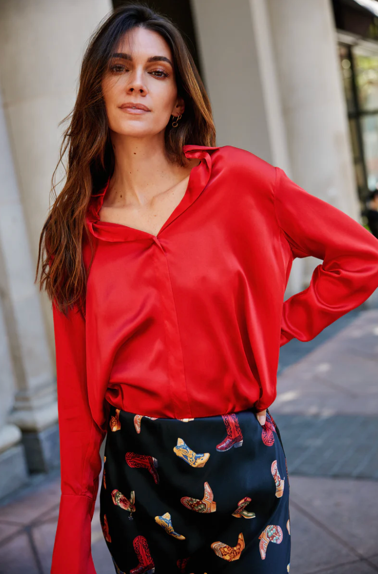 Woman wearing a red blouse and patterned skirt outdoors