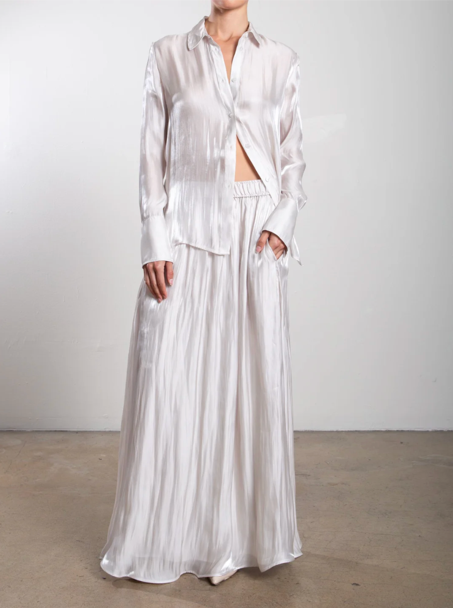 Person wearing a white pleated outfit against a plain background