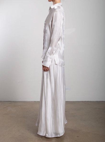 Person wearing a long, light-colored dress against a plain background