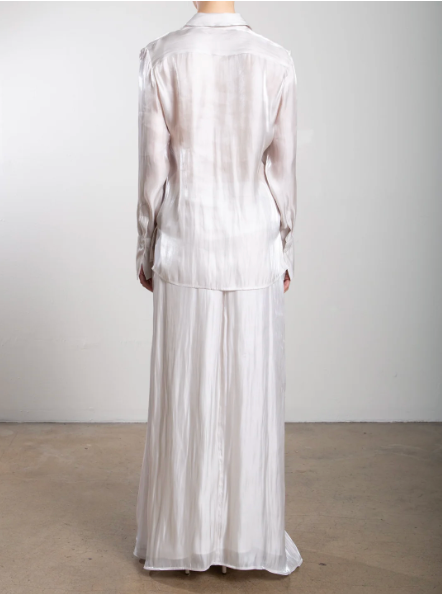 Mannequin wearing a light-colored outfit with a long skirt against a plain background