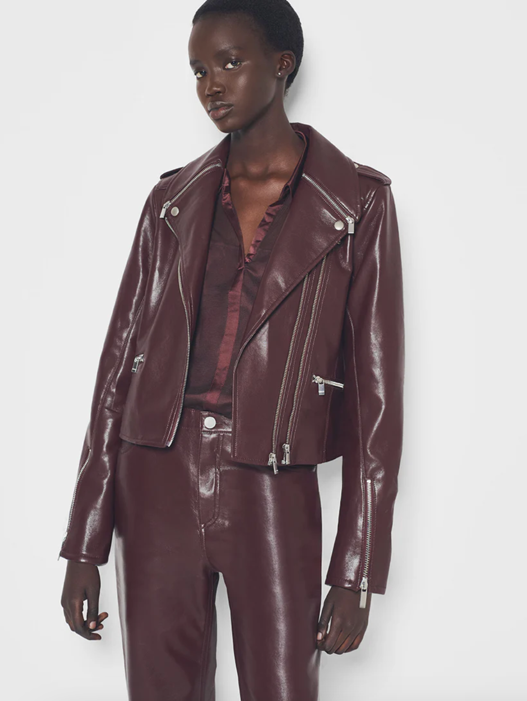 Person wearing a brown leather jacket and pants on a white background