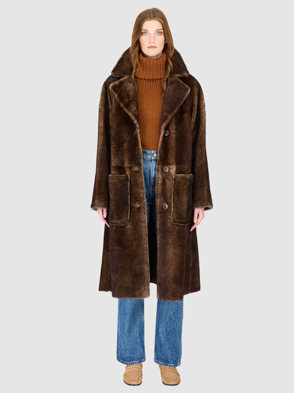 Person wearing a brown shearling coat on a white background